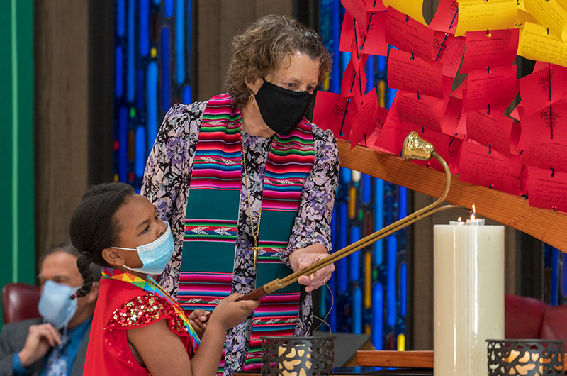 child and pastor light a candle together