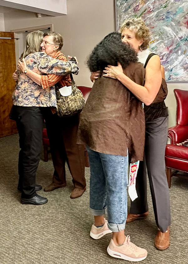 two pairs of people hugging while gathering at sunday worship