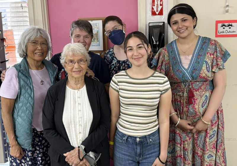 Pink Cow Thrift Store volunteers standing together in front of a pink wall