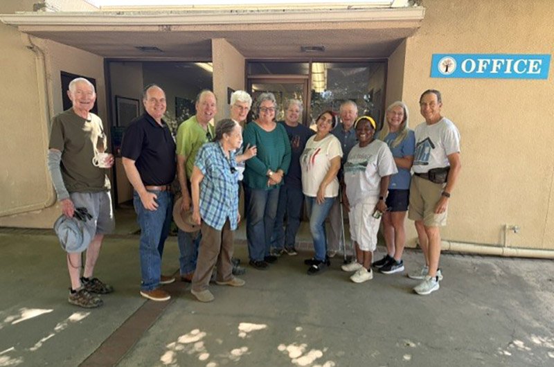 group of smiling adults standing in front of the church office building